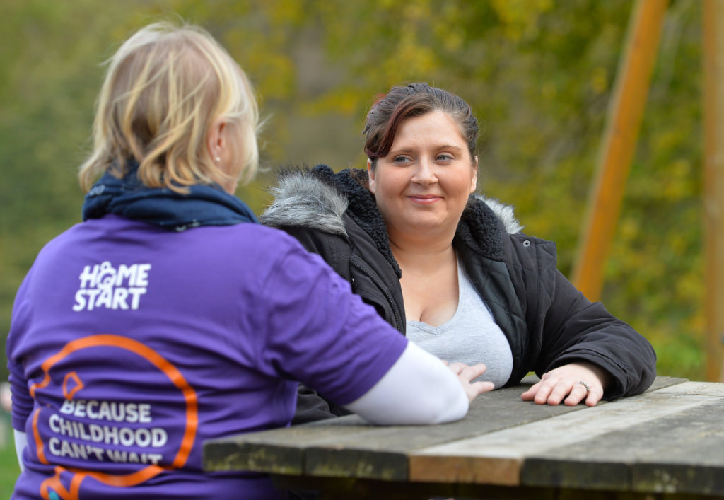 Volunteer-talking-to-a-mum-outside-on-bench